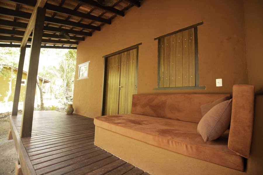 The exterior of a cottage with a built-in earthen sofa on the deck
