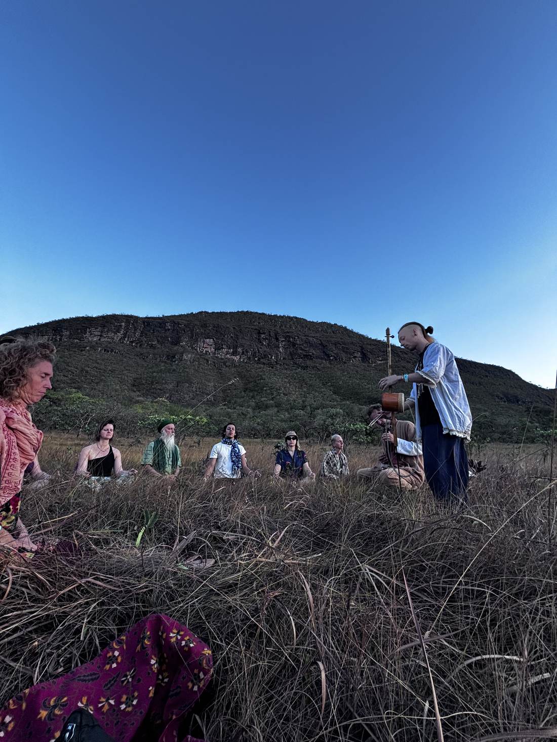 Group sitting in meditation in the open Cerrado at golden hour