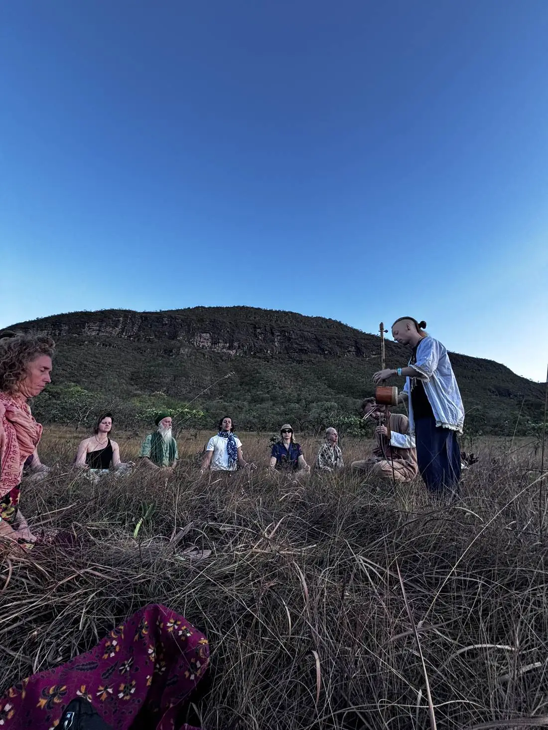 Group sitting in meditation in the open Cerrado at golden hour