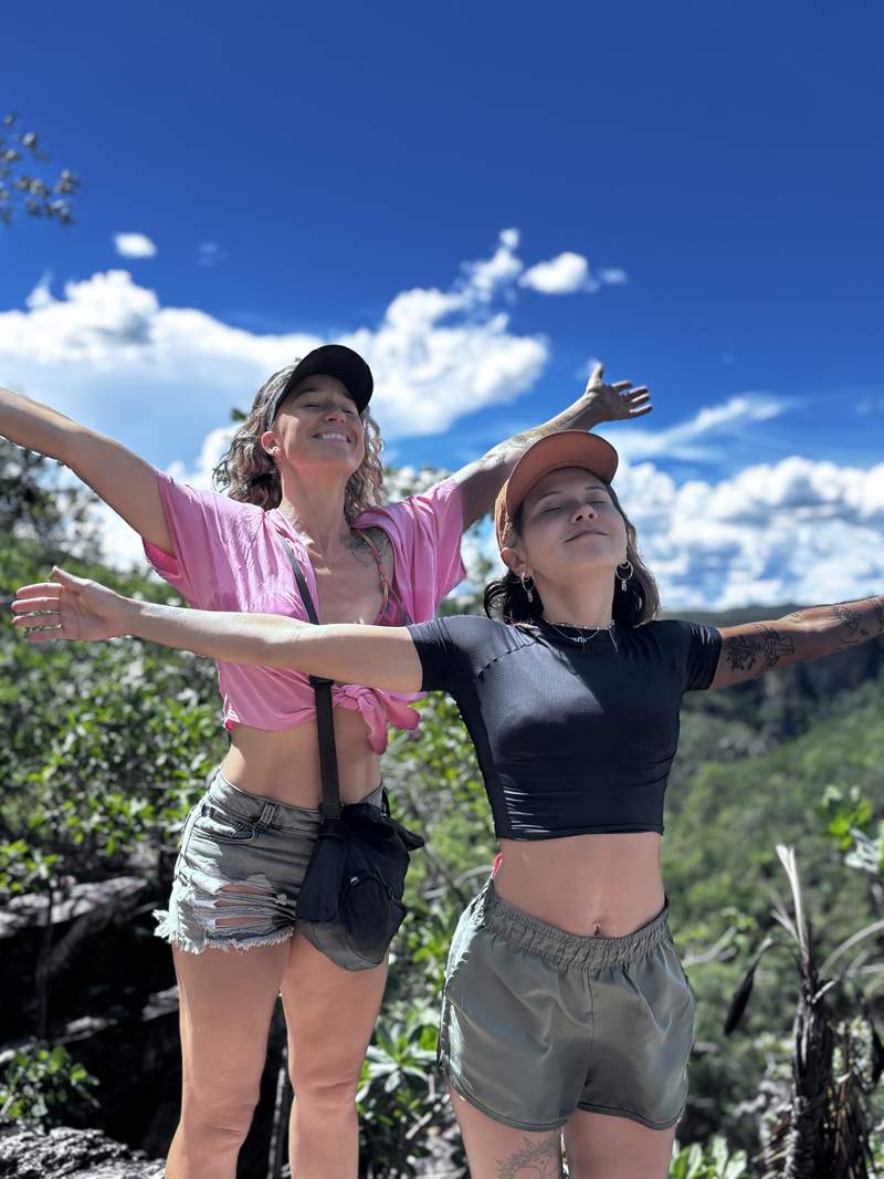 Two women on a mountain summit, arms open
