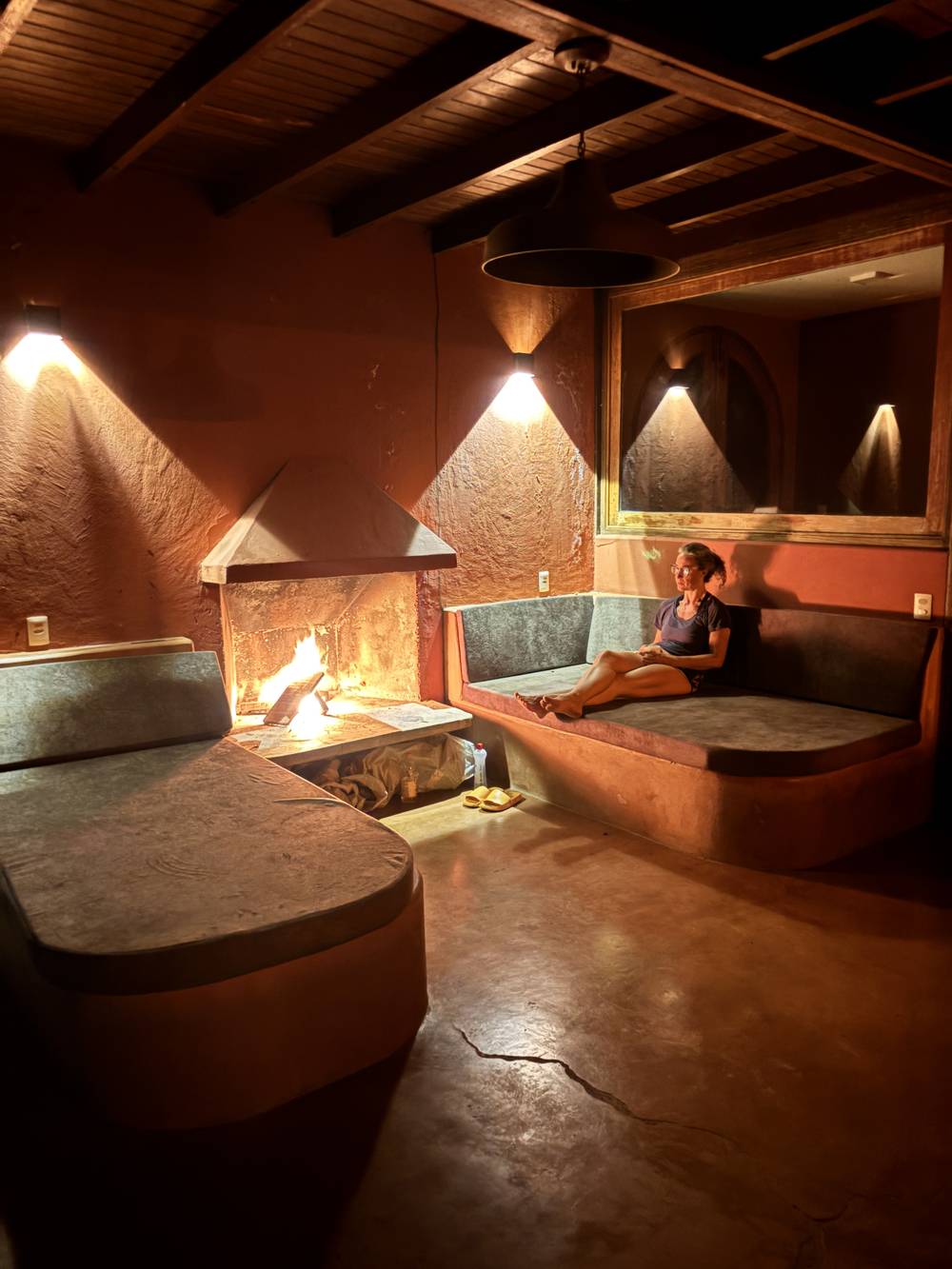 Fireplace lounge with stone divans and warm earthen walls