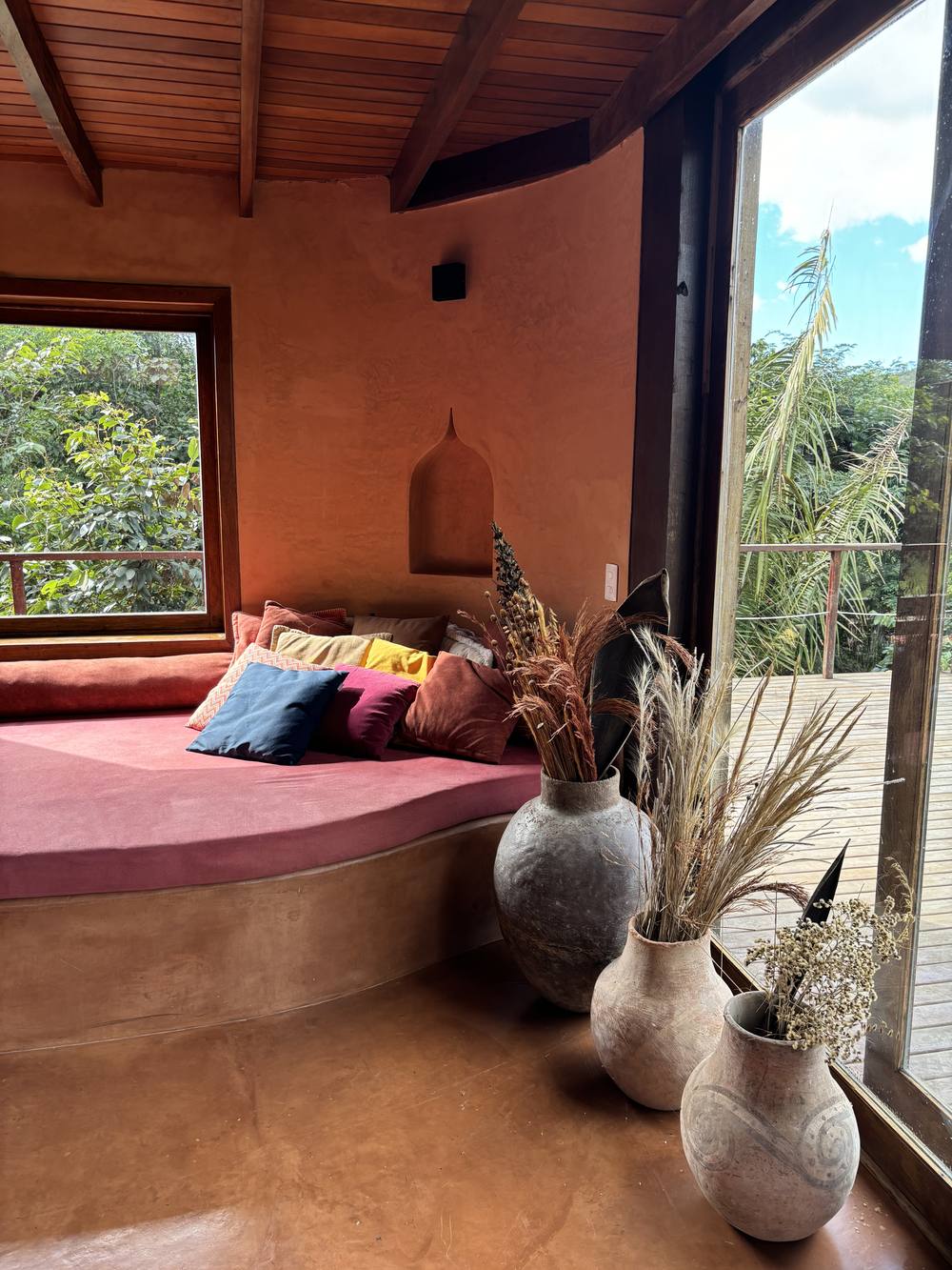 Reading nook with a pink divan, mughal niche and ceramic vases