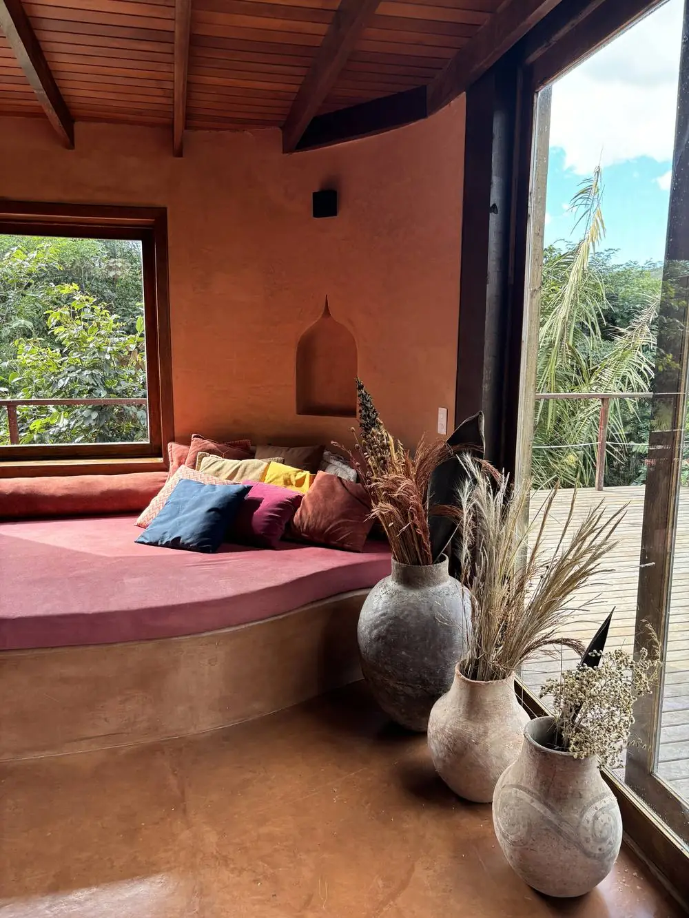 Reading nook with a pink divan, mughal niche and ceramic vases